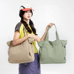Detail of large nylon tote bag featuring side drawstrings and comfortable wide straps