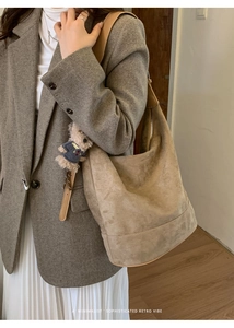 Detail of suede hobo bag with teddy bear charm worn with a classic wool coat