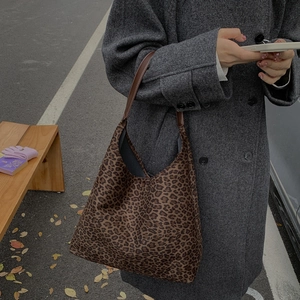 Detailweergave van de shopper met luipaardprint en bruine lederen handgrepen