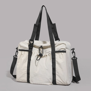 Detail of a beige large travel tote bag with black nylon straps and buckle closures