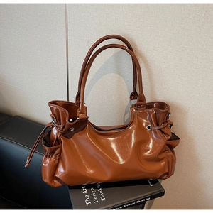 Détail d'un sac cabas en cuir marron brillant avec cordons de serrage et poignées