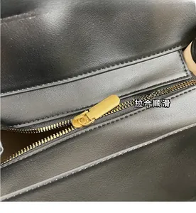 Vue détaillée de la fermeture éclair en métal doré et des coutures du sac en cuir noir