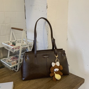 Detail of dark brown tote bag with dual straps and a cute plush bear charm accessory
