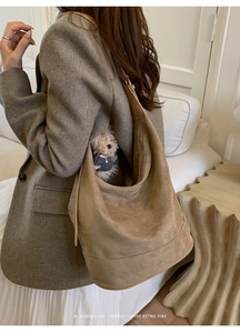 Detail shot of a brown suede hobo tote bag featuring a cute teddy bear charm