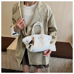 Detail der weißen Kunstfell-Handtasche mit Holzperlenquaste und abnehmbarem Gurt