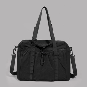 Detail of black nylon tote bag showing front drawstring pocket and durable texture