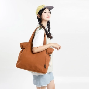 Detail view of brown large capacity tote bag with drawstring side and wide shoulder strap