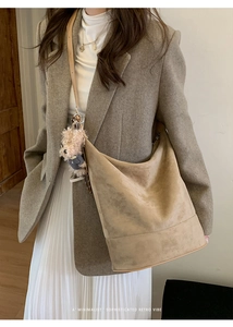 Close-up of brown suede hobo bag texture with cute bear charm on a minimalist model look