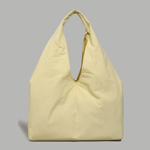 Detailed close-up of cream yellow nylon tote bag with minimalist seamless handle