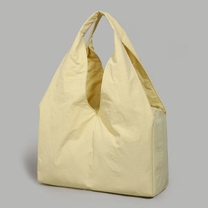 Detail of light yellow nylon tote bag showing textured fabric and wide shoulder strap