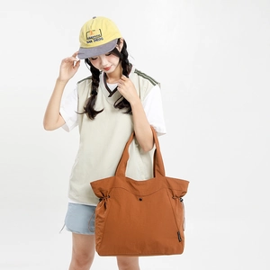 Detail view of large caramel tote bag with drawstring sides and secure snap closure