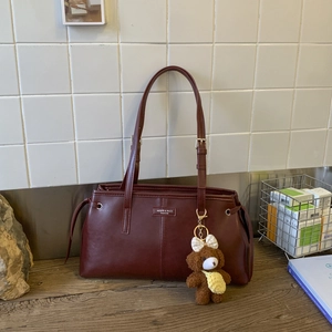 Dettaglio borsa shopper bordeaux con logo e ciondolo a forma di orsetto di peluche