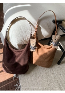 Detail of suede hobo bags in dark brown and caramel colors with plush bear charm decor