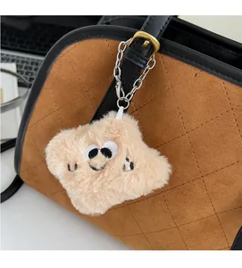 Vue détaillée du porte-clés monstre en peluche beige sur un sac à main marron matelassé