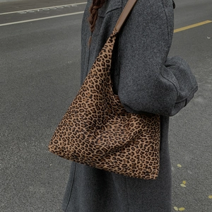 Detail van de hobo-tas met luipaardprint gedragen door een model in grijze jas