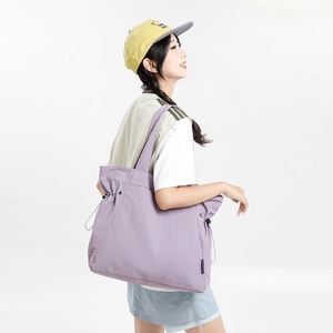 Detail of light purple large tote bag with drawstring closure on model's shoulder