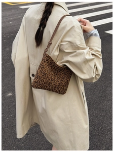 Dettaglio della borsa leopardata con tracolla in pelle marrone su trench beige