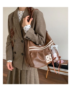 Dettaglio borsa a tracolla in pelle marrone retrò con patch 89 e fiocco in pizzo