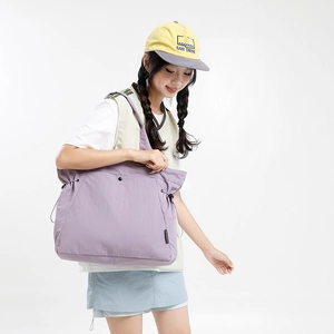 Detail of lilac nylon tote bag featuring drawstring pleats and durable metal snap closure