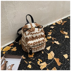 Nahaufnahme eines flauschigen Mini-Rucksacks mit Fleckenmuster und schwarzen Lederriemen