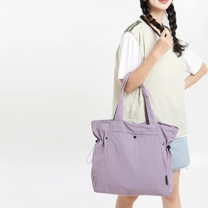 Detail view of a lavender nylon tote bag with drawstring side and snap button closure