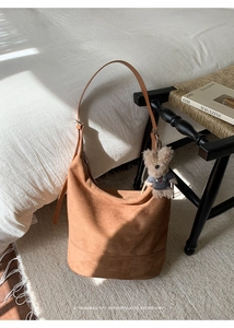 Brown suede bucket bag with adjustable strap and cute plush bear charm detail