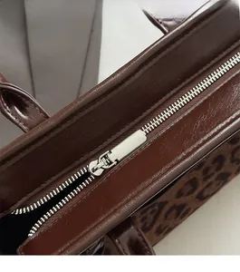 Détail macro du zip en métal argenté et imprimé léopard sur sac en cuir marron
