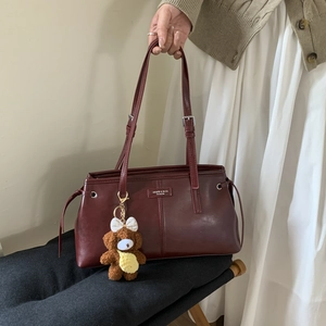 Dettaglio borsa a spalla in pelle PU bordeaux con ciondolo a orsetto e tracolla