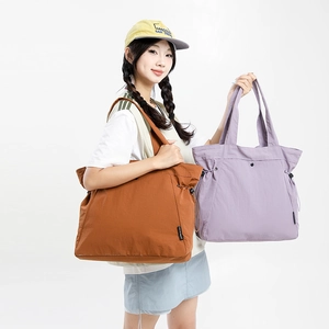 Detail view of large tote bags in brown and purple showing nylon fabric and drawstring design
