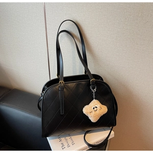 Détail du sac à main noir matelassé avec surpiqûres en losange et breloque en peluche