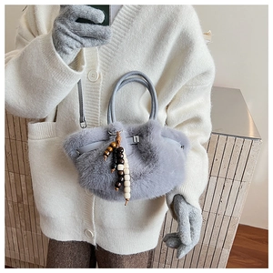 Detail einer Plüschtasche aus Kunstpelz mit Holzperlen-Anhängern und Ledergriffen