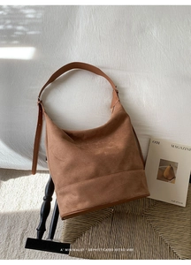 Detail of vintage brown suede hobo bag with adjustable strap on a woven chair