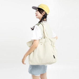 Detail of off-white canvas tote bag featuring adjustable drawstring and spacious interior