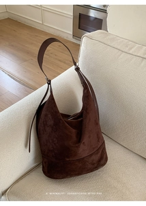 Detailed texture of a large dark brown suede hobo bag placed on a minimalist sofa