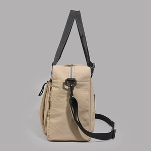 Detail of khaki nylon travel tote featuring a drawstring side pocket and durable strap