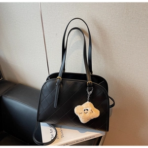 Détail d'un sac cabas noir matelassé avec boucles en bronze et breloque étoile jaune