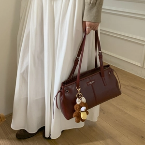 Dettaglio della borsa tote in pelle bordeaux con ciondolo a forma di orsetto