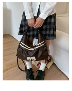 Dettaglio della borsa tote vintage marrone con strisce bianche e toppa 89 sul modello