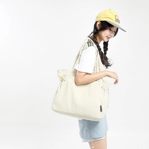 Detail of light beige tote bag featuring functional side drawstring and large capacity