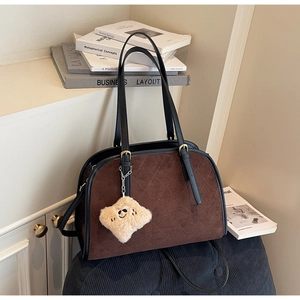 Détail d'un sac à main rétro en daim marron avec surpiqûres et breloque toast peluche