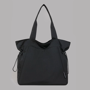 Detail of black large capacity tote bag featuring nylon texture and side drawstring design