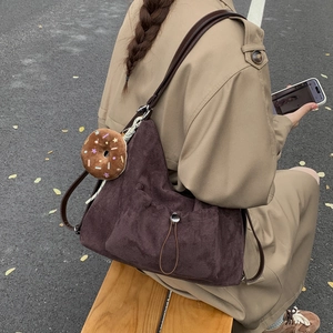 Detalle de bolso de ante con bolsillo de cordón y accesorio de amuleto de donut de peluche