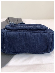 Detail of the bottom structure and white contrast stitching on the dark blue denim bag