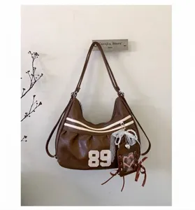 Dettaglio di zaino vintage marrone con toppa 89 e ciondolo in pizzo elegante
