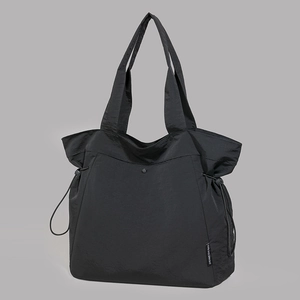 Close-up of black nylon tote bag with drawstring detail and metallic snap button closure