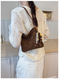 Dettaglio borsa a spalla leopardata con nappa di perline boho e texture scamosciata liscia