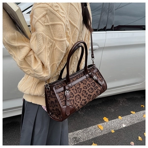 Detail der Handtasche mit Leopardenmuster, Lederbesatz und dekorativer Metallschnalle