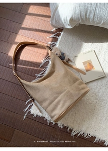 Detail view of khaki suede bucket bag on textured floor with sunlight shadows