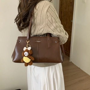 Dettaglio laterale della borsa tote vintage marrone con un simpatico ciondolo a orsetto