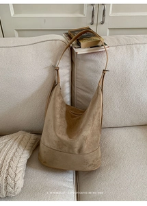 Close-up of khaki suede hobo bag on sofa with retro vibe and minimalist design